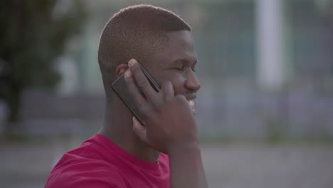 Closeup-of-Afro-American-man-talking-on-phone-in-park,-smiling